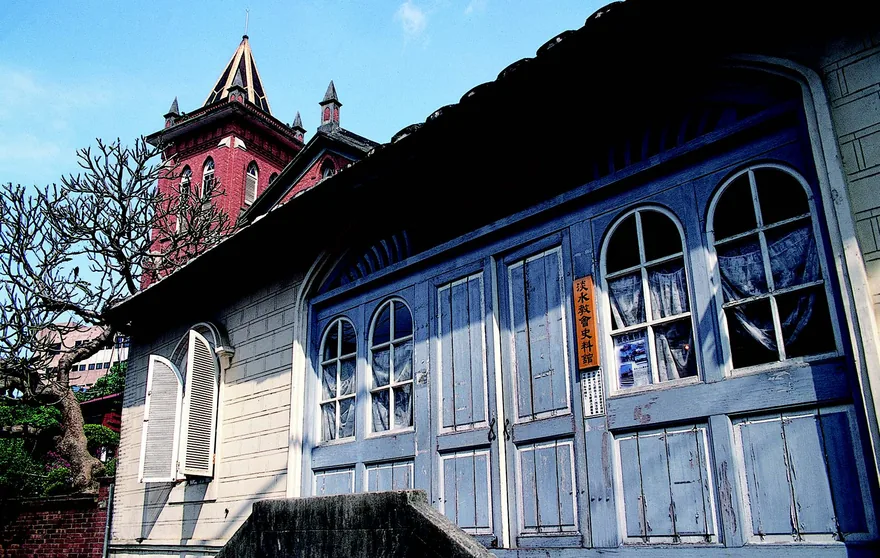 建於 1879 年 9 月 14 日 的「滬尾偕醫館」,是臺 灣北部首間西醫院。清法 戰爭時因救助清勇無數而 獲軍功。照片約攝於1895 年,馬偕博士站於門口。 「滬尾偕醫館」今日仍保 存在淡水教會禮拜堂東鄰, 也是淡水知名古蹟。